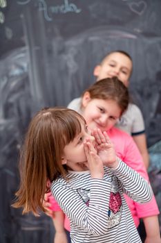 group portrait of happy childrens standing one behind the other while having fun in front of black chalkboard