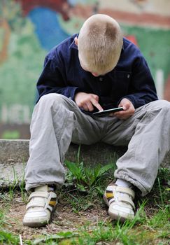 young blonde boy playing videogames outdoor in park