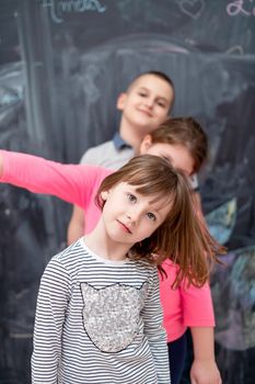 group portrait of happy childrens standing one behind the other while having fun in front of black chalkboard