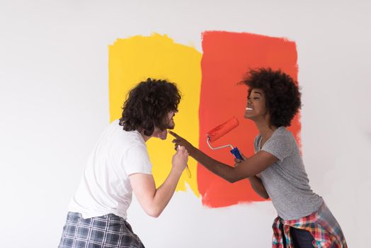 happy young multiethnic couple painting interior wall of new house