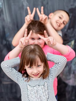 group portrait of happy childrens standing one behind the other while having fun in front of black chalkboard