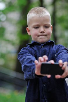 young blonde boy playing videogames outdoor in park