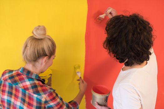 happy smiling young couple painting interior wall of new house