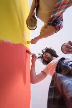 happy smiling young couple painting interior wall of new house