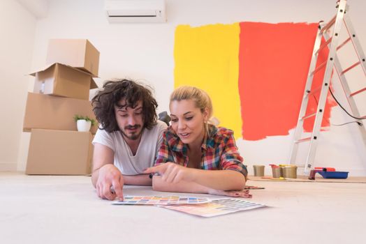 Happy young couple relaxing after painting a room in their new house on the floor