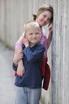 young boy and girl standing over iron fence at day and representing urban and fashion concept for child