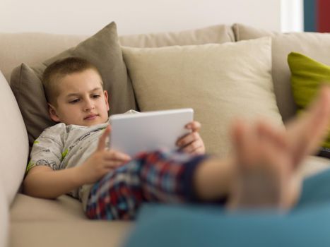 little boy playing video games on tablet computer at home