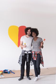 Portrait of loving multiethnict couple with painted heart on wall