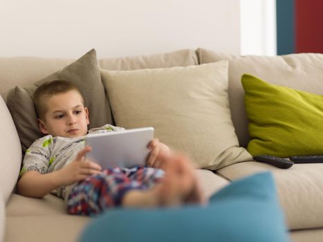 little boy playing video games on tablet computer at home