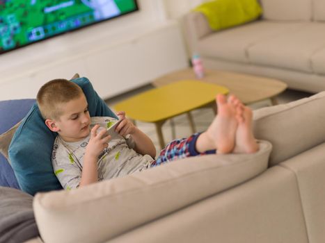 little boy playing video games on smartphone at home