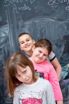 group portrait of happy childrens standing one behind the other while having fun in front of black chalkboard