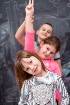 group portrait of happy childrens standing one behind the other while having fun in front of black chalkboard