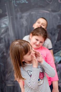 group portrait of happy childrens standing one behind the other while having fun in front of black chalkboard