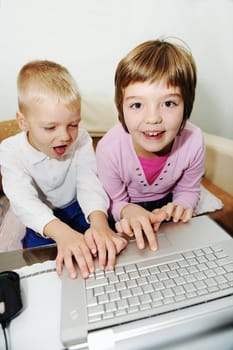 two happy children playing games and learnig education lessons on laptop computer at home