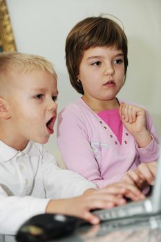 two happy children playing games and learnig education lessons on laptop computer at home