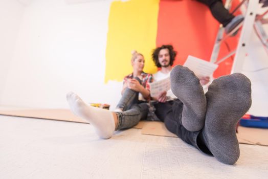 Happy young couple relaxing after painting a room in their new house on the floor