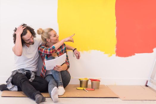 Happy young couple relaxing after painting a room in their new house on the floor