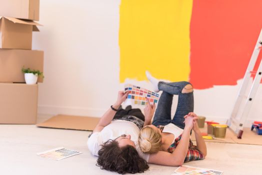 Happy young couple relaxing after painting a room in their new house on the floor