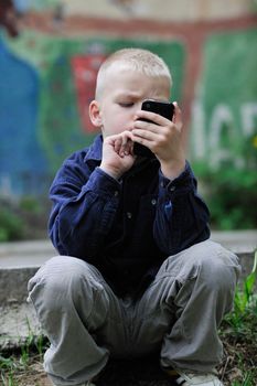 young blonde boy playing videogames outdoor in park