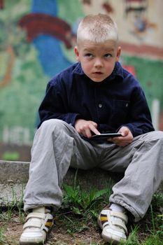 young blonde boy playing videogames outdoor in park