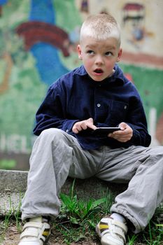 young blonde boy playing videogames outdoor in park