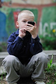 young blonde boy playing videogames outdoor in park