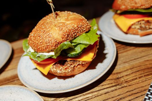 cheeseburgers and fries on table top with onion, tomato, lettuce and cheese.