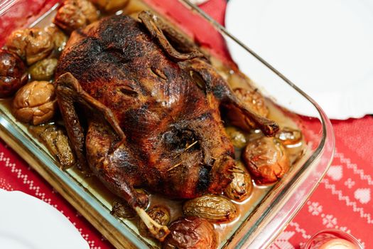 A close-up of a crispy baked goose in its own fat with potatoes and apples, at Christmas dinner. High quality photo