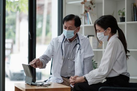 Senior asian doctor physician consulting young female patient, talking to client at medical checkup visit. Geriatric diseases treatment. Elderly medical health care concept