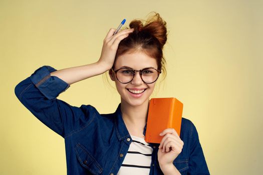 woman student with glasses notepad with pen yellow background. High quality photo