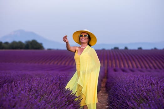 beautiful young asian woman in yellow dress and hat relaxing and having fun on purple flower lavender field
