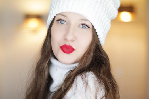 Christmas, people and winter holiday concept. Beautiful woman wearing red lipstick makeup sending a kiss, closeup face xmas portrait.