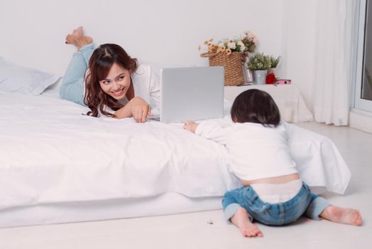 Young adult mother trying to work and spend time with little daughter.