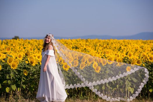 Young happy Asian woman in wedding dress having fun and relax on Sunflower field