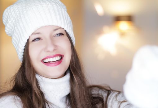 Christmas, people and winter holiday concept. Happy smiling woman wearing white knitted hat as closeup face xmas portrait.