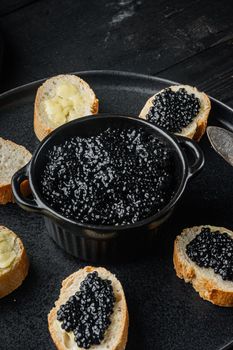 Sandwiches with black caviar and butter, on black wooden table background