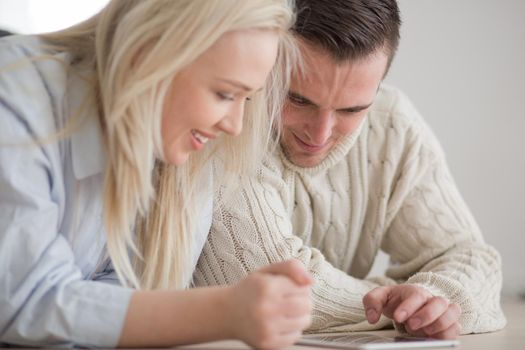 Young Couple on the floor in front of fireplace surfing internet using digital tablet on cold winter day