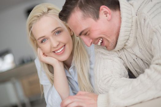 Young Couple on the floor in front of fireplace surfing internet using digital tablet on cold winter day