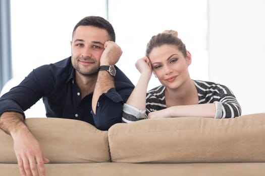 Portrait of young couple sitting on sofa in modern white apartment