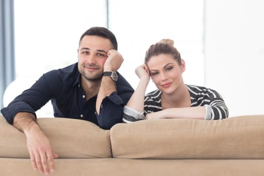 Portrait of young couple sitting on sofa in modern white apartment