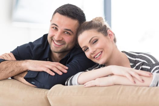 Portrait of young couple sitting on sofa in modern white apartment