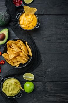 Mexican food concept. Nachos - yellow corn totopos chips with various sauce, on black wooden background, top view or flat lay with copy space for text