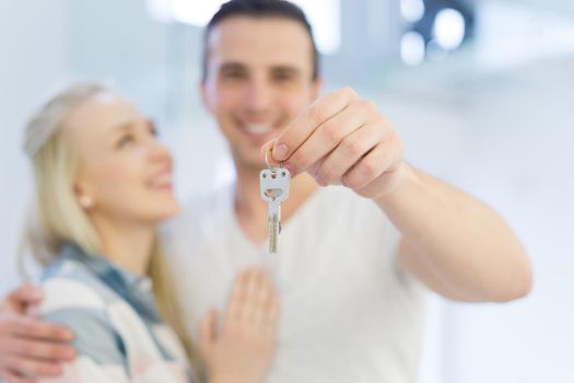 Happy smiling young couple hugging while showing a keys of their new house