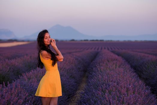 beautiful young woman in yellow dress relaxing and having fun on purple flower lavander field