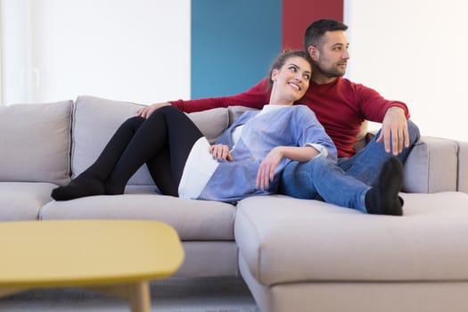 Happy young couple hugging and relaxing on sofa at home