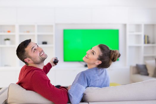 Young couple on the sofa watching television together in their luxury home