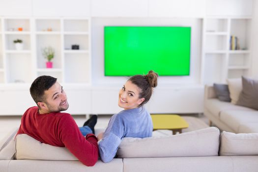 Young couple on the sofa watching television together in their luxury home