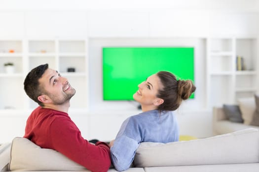 Young couple on the sofa watching television together in their luxury home