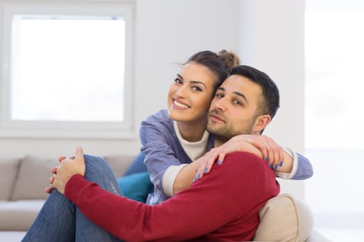 Happy young couple hugging and relaxing on sofa at home