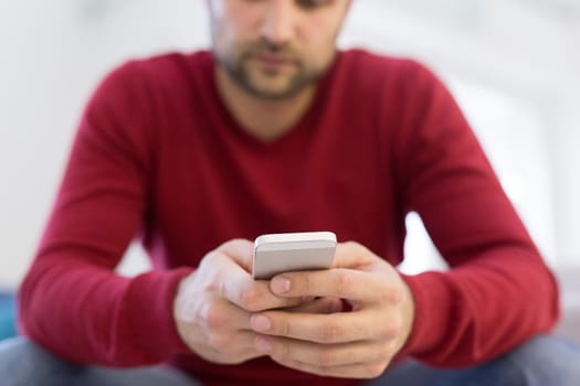 Handsome casual young man using a mobile phone at  home